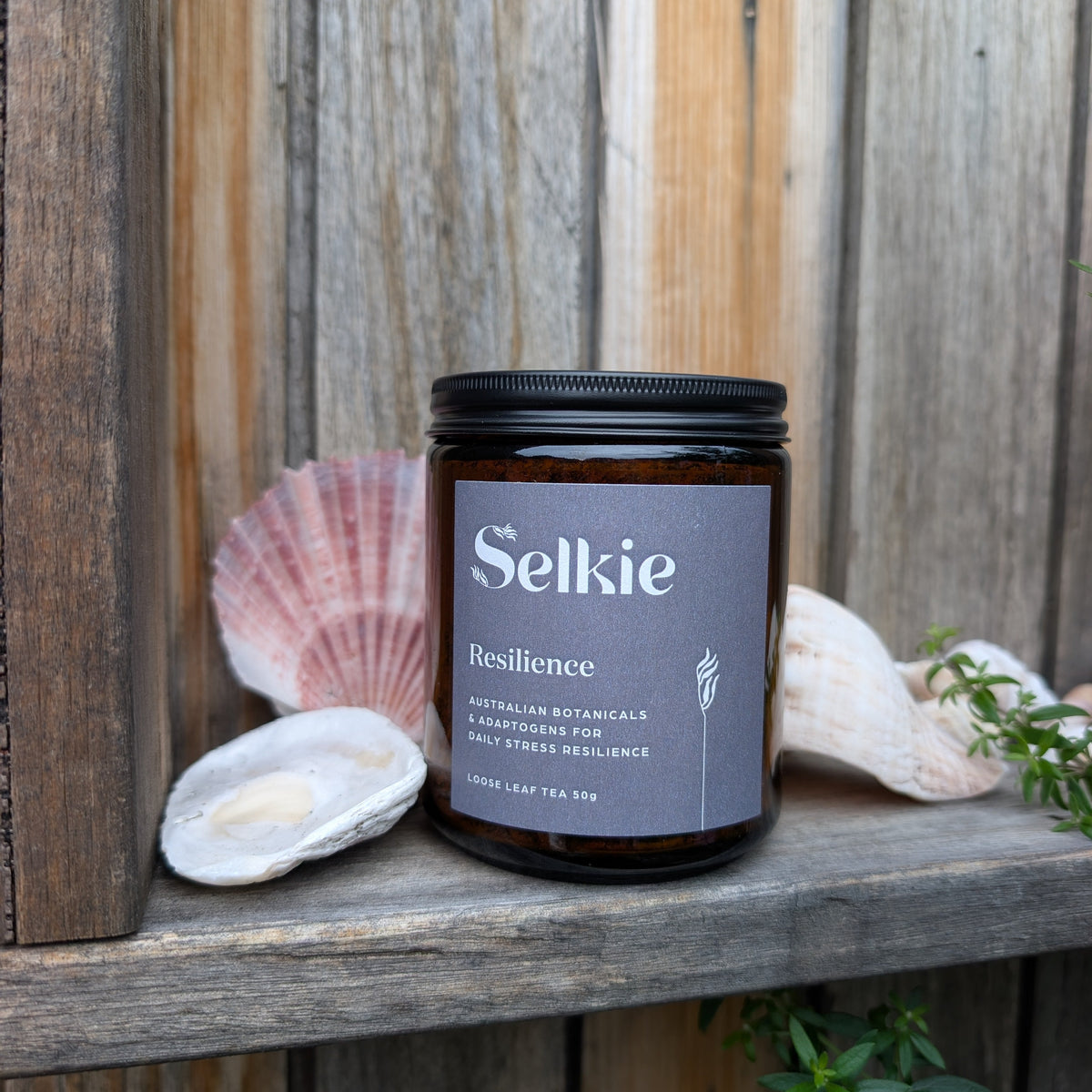 Selkie tea labeled 'Resilience' on a wooden surface with seashells and plants.