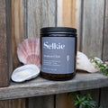 Selkie tea labeled 'Awaken Chai' on a wooden surface with seashells and plants.
