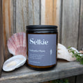 Selkie Kakadu Plum on a wooden surface with seashells and plants in the background