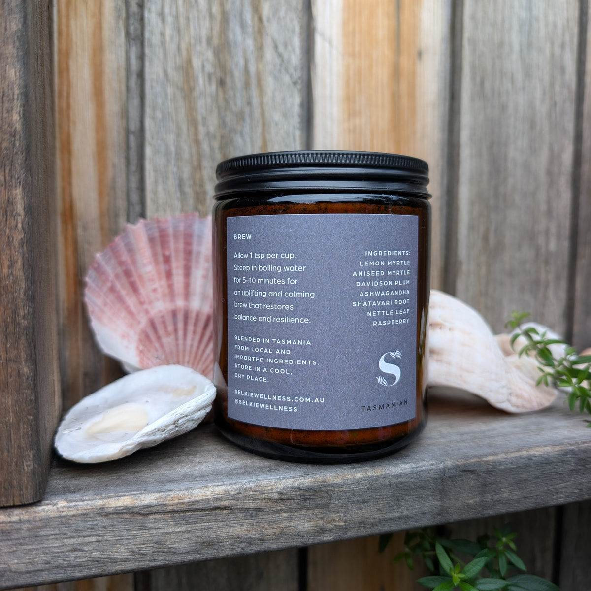 Jar of tea with a label on a wooden surface with shells and plants