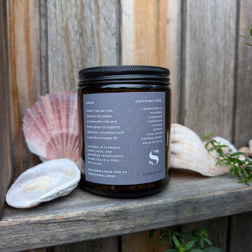 Black jar with label on a wooden surface with seashells and plants